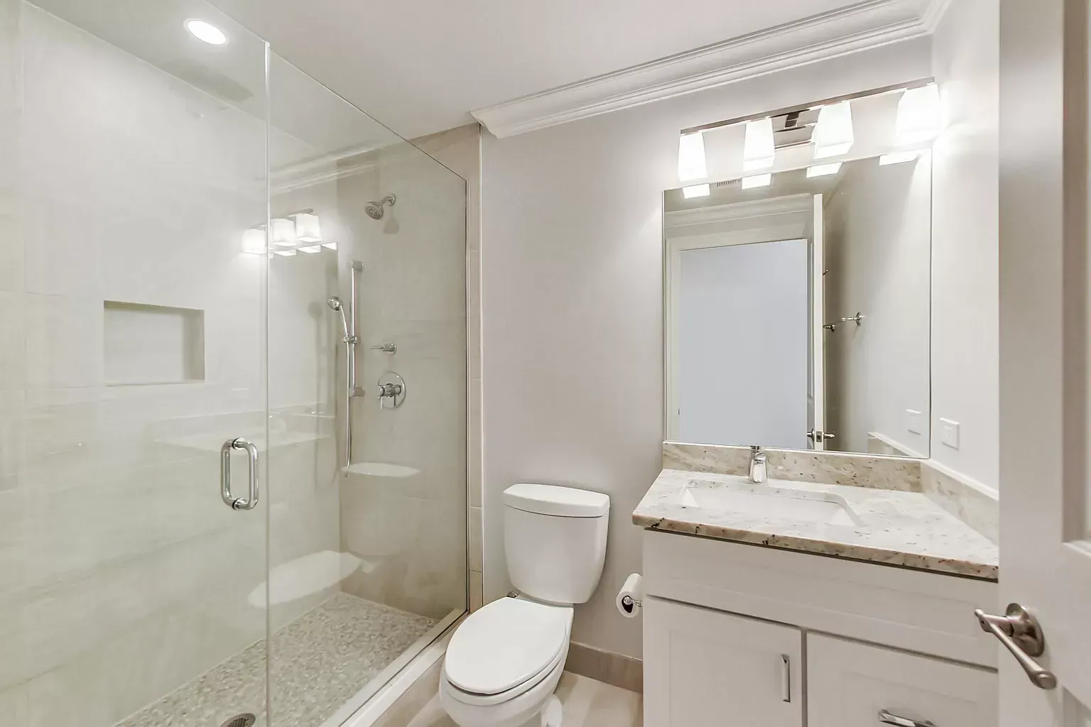 a bathroom with a toilet , sink , shower and mirror .