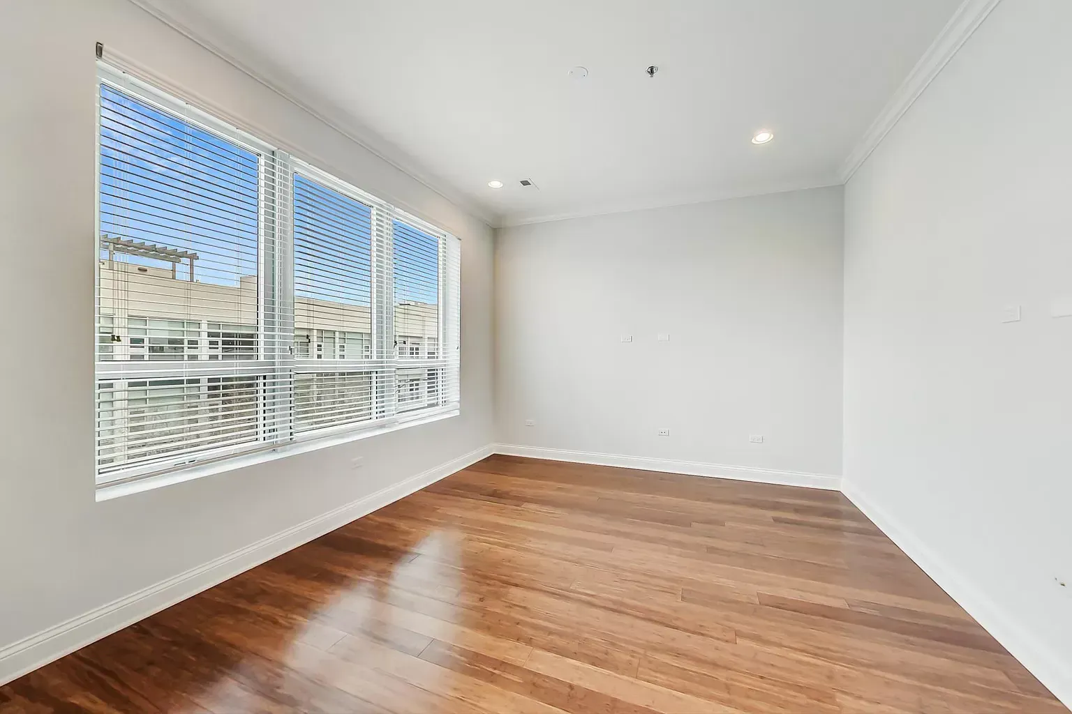 an empty room with hardwood floors and a large window .