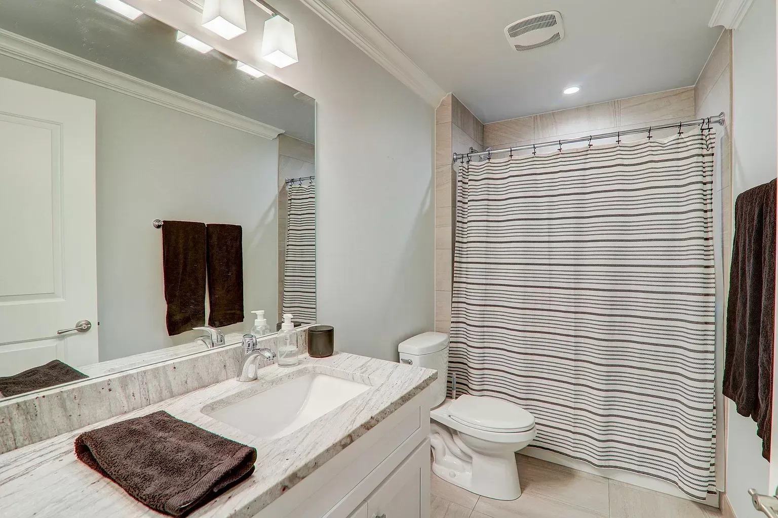 a bathroom with a toilet , sink , mirror and shower curtain .