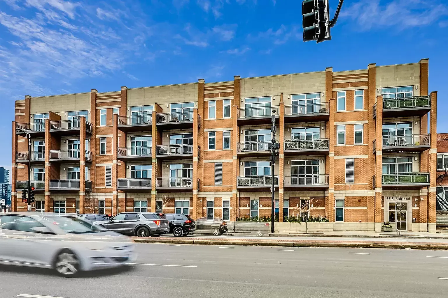 a white car is driving down a street in front of a large brick building .