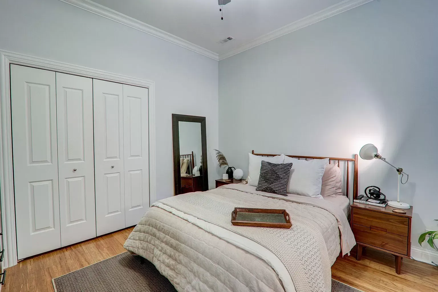 a bedroom with a bed , nightstand , mirror and closet .