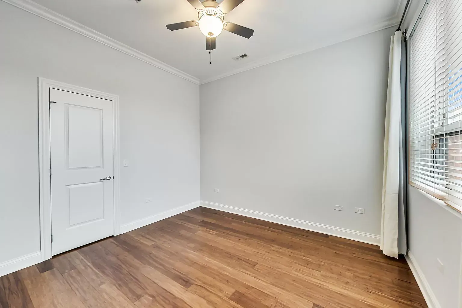 an empty bedroom with hardwood floors and a ceiling fan .