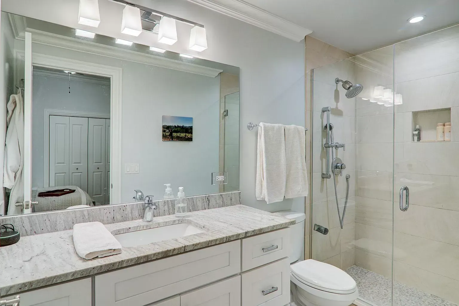a bathroom with a toilet , sink , mirror and shower .
