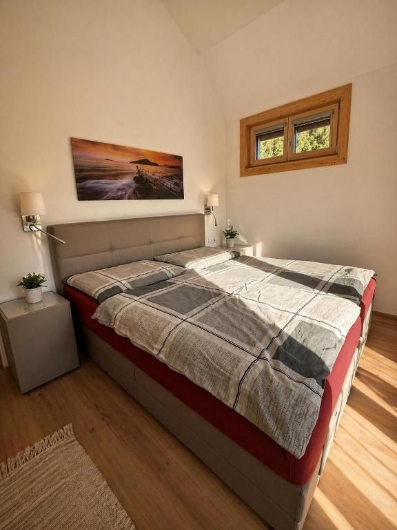 Gemütliches Schlafzimmer mit einem ordentlich gemachten Bett, Nachttischen, Wandbildern und einem kleinen Fenster