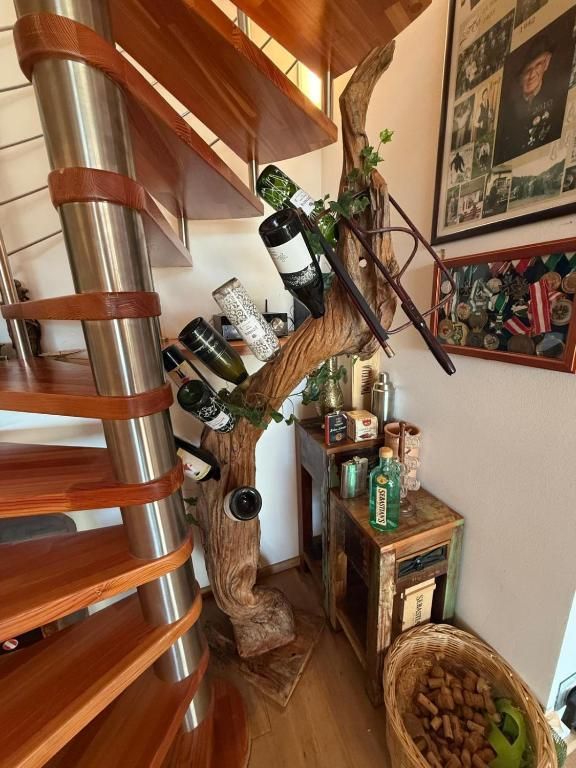 Eine geschwungene Holztreppe neben einem dekorativen Baumregal mit Flaschen, Dosen und Pflanzen in einem gemütlichen Zimmer