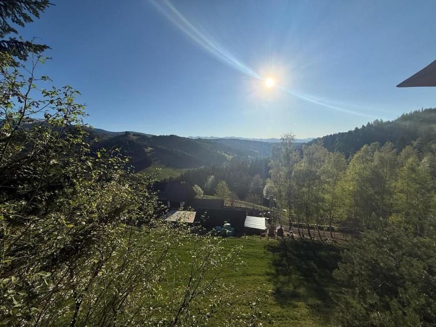 Sonniges Bergtal mit Bäumen, Hügeln und strahlend blauem Himmel