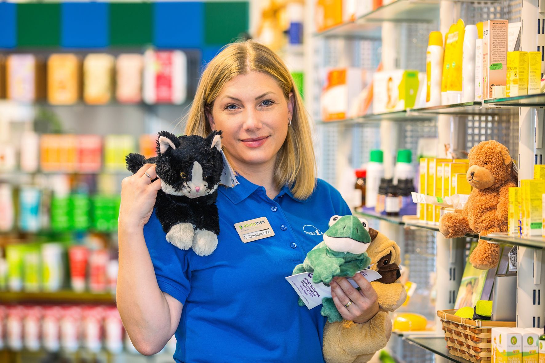 Eine Frau hält in einer Apotheke zwei Stofftiere.
