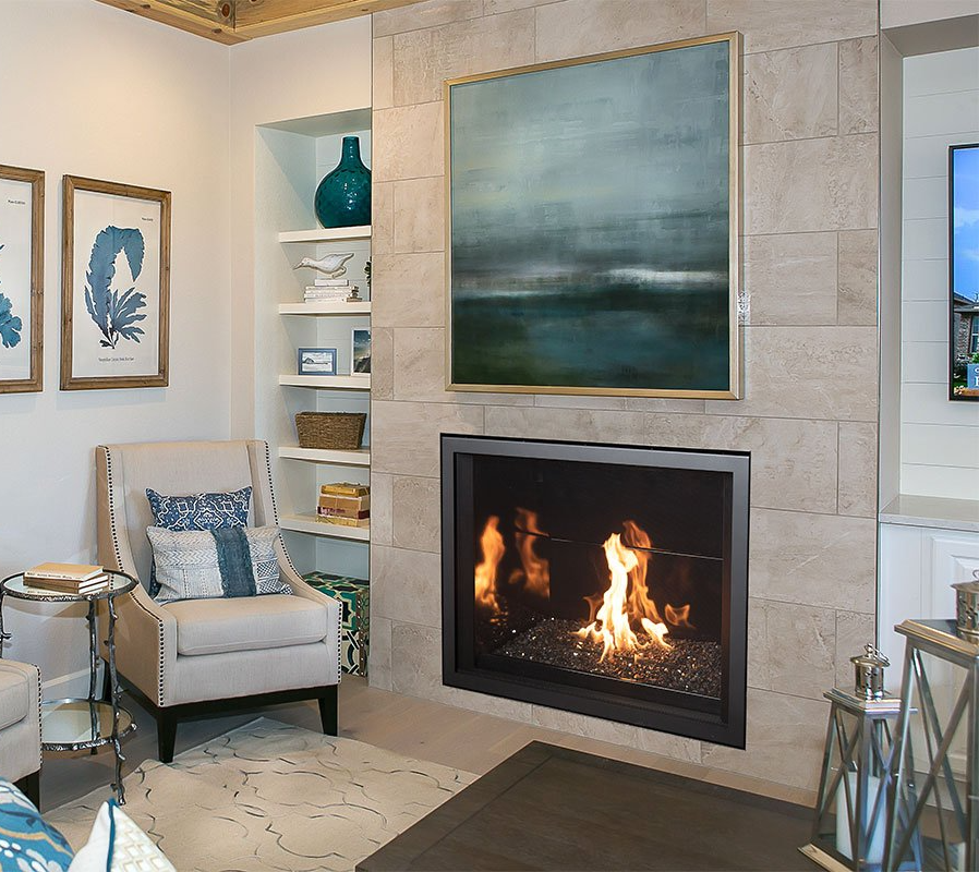 Cozy living room with fireplace, abstract painting, built-in shelves with decor, and a soft armchair.