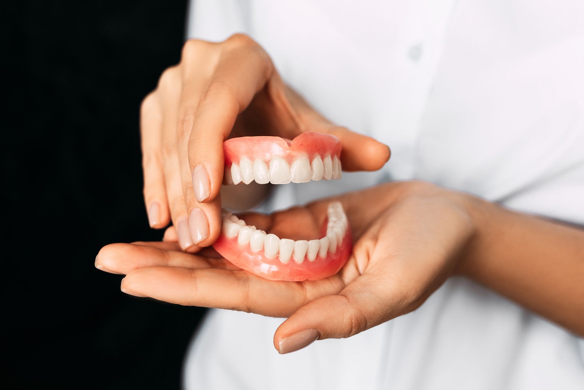 Close-up of a dentist holding a new denture prosthesis.