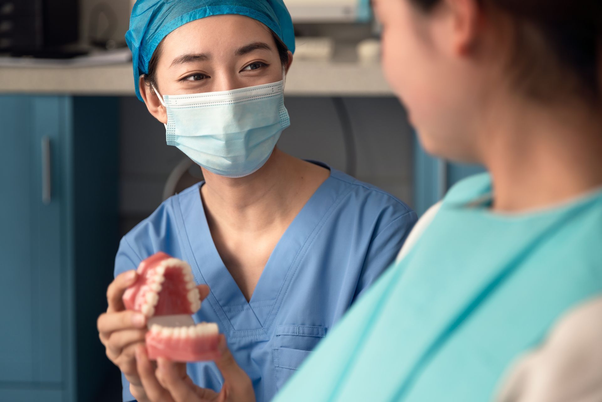 The dentist shows the dental model to the patient in a clinic setting.