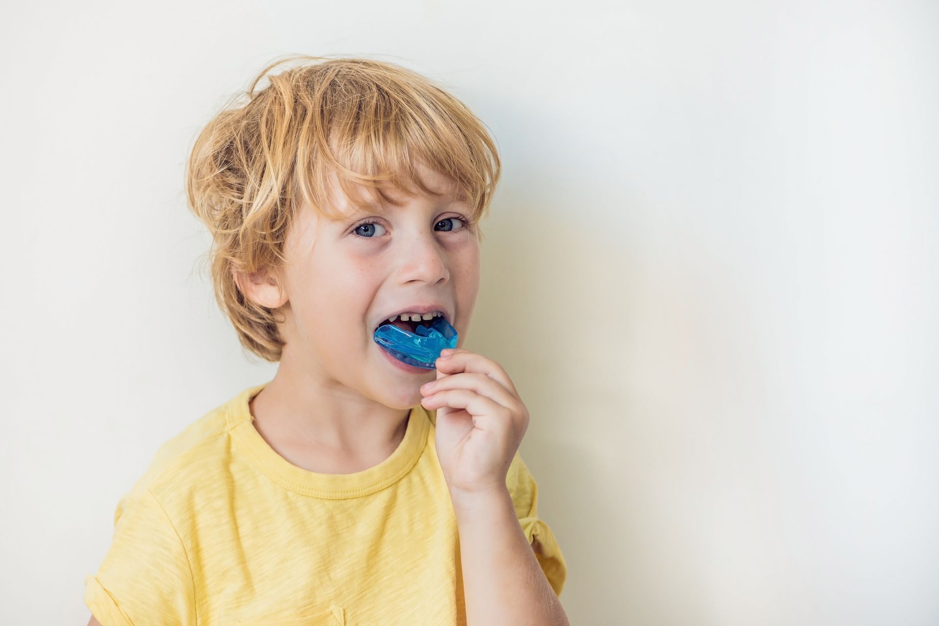 A young boy is wearing a blue mouth guard