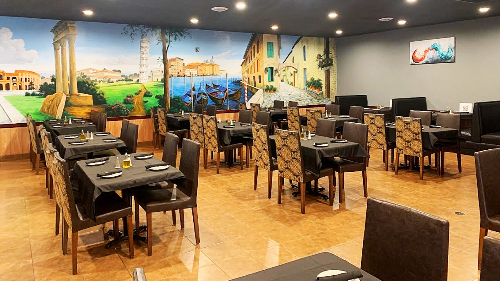 Restaurant interior with tables, chairs, and a mural of a coastal scene.