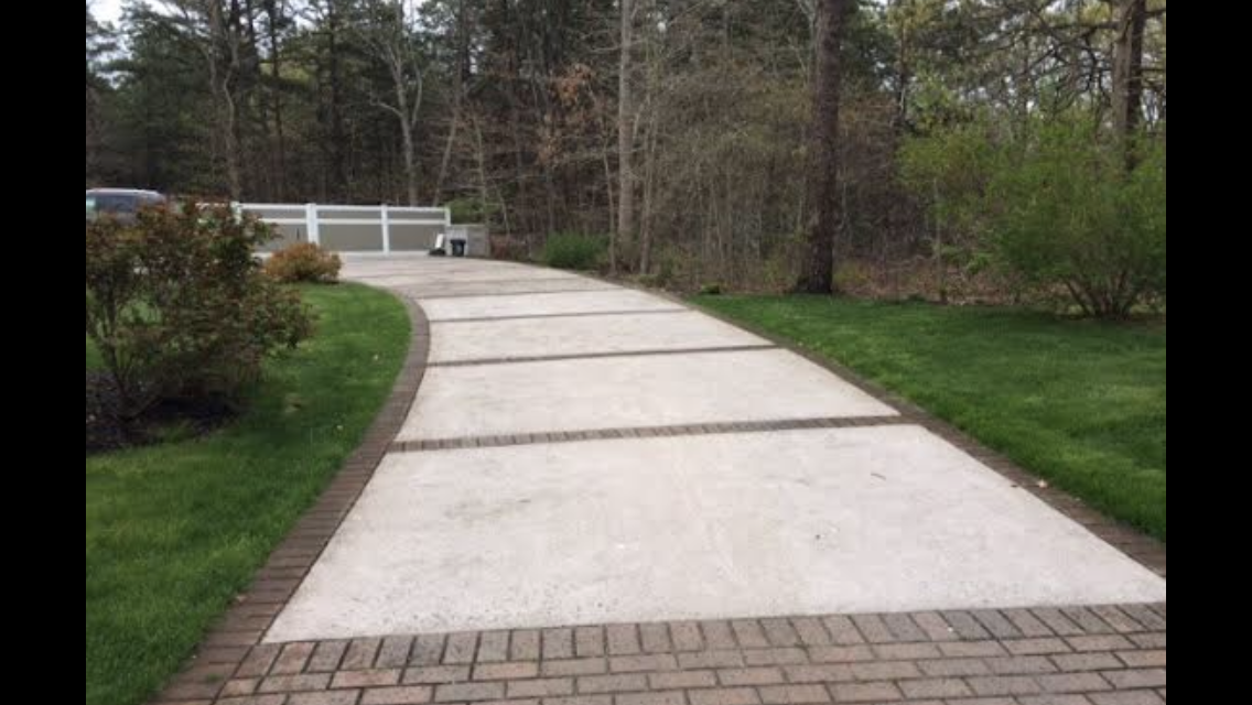 A brick driveway leading to a house in the woods.
