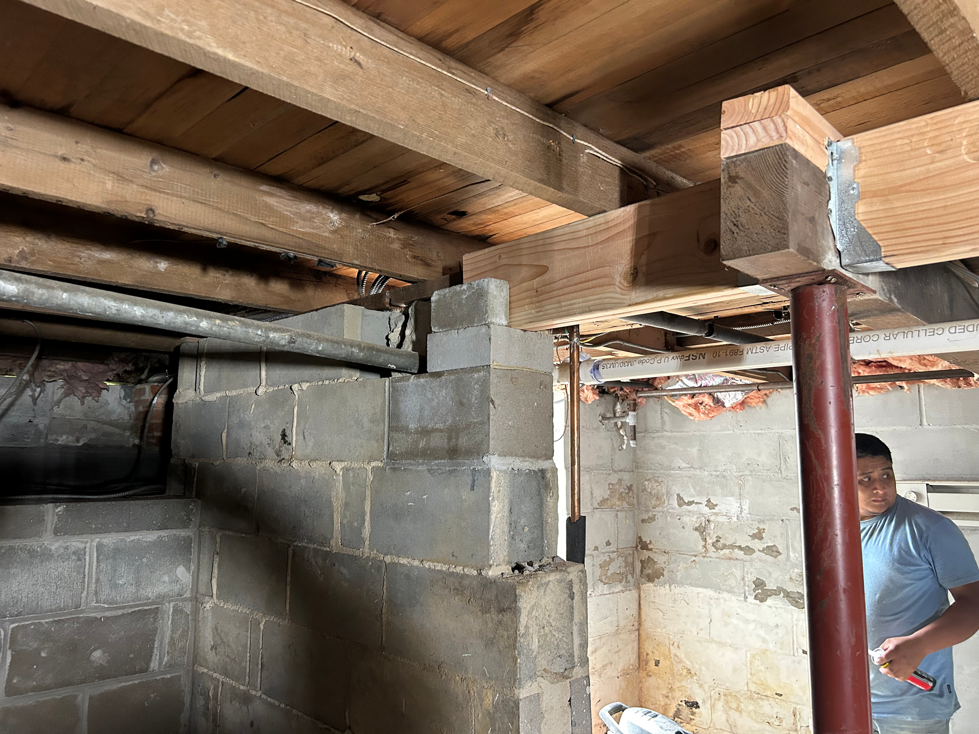 A man is standing in a basement under a wooden ceiling.