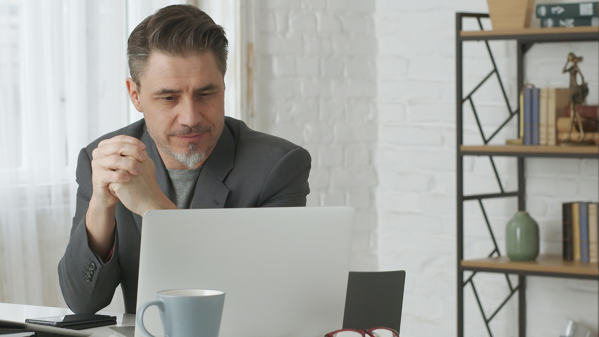 A man is sitting at a desk in front of a laptop computer.