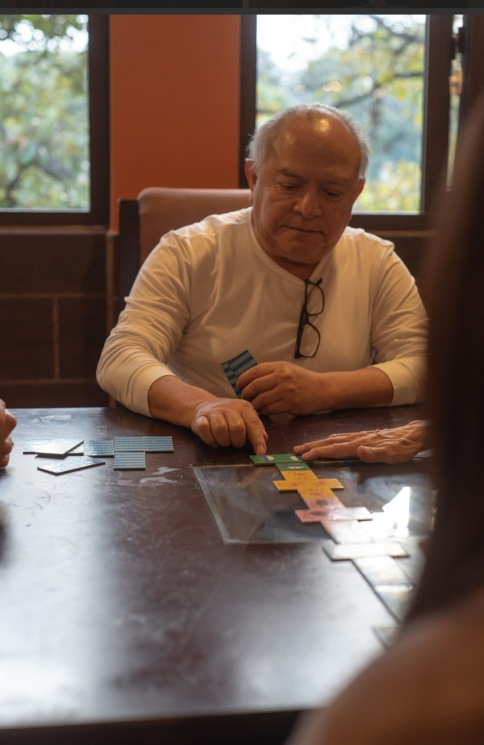 Persona sentada a una mesa, examinando documentos en una sala de reuniones con iluminación cálida.