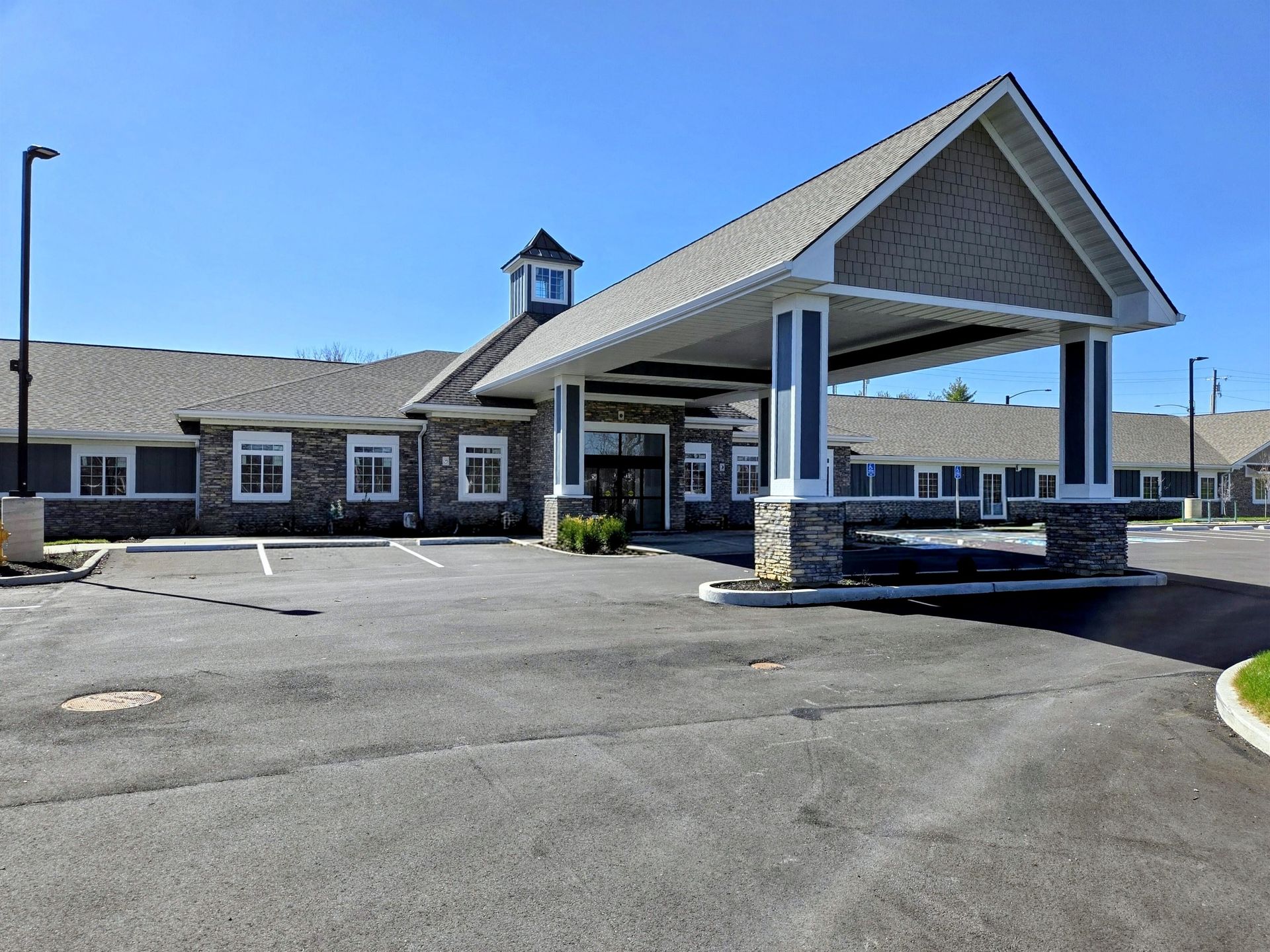 Covered driveway entrance of a stone building with a large white canopy and empty parking lot