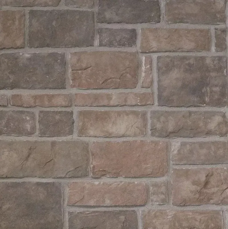 Close-up of a gray and beige stone brick wall with a rough textured surface