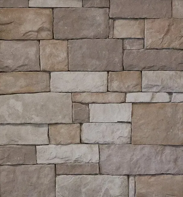 Stacked beige and gray stone wall with uneven rectangular blocks