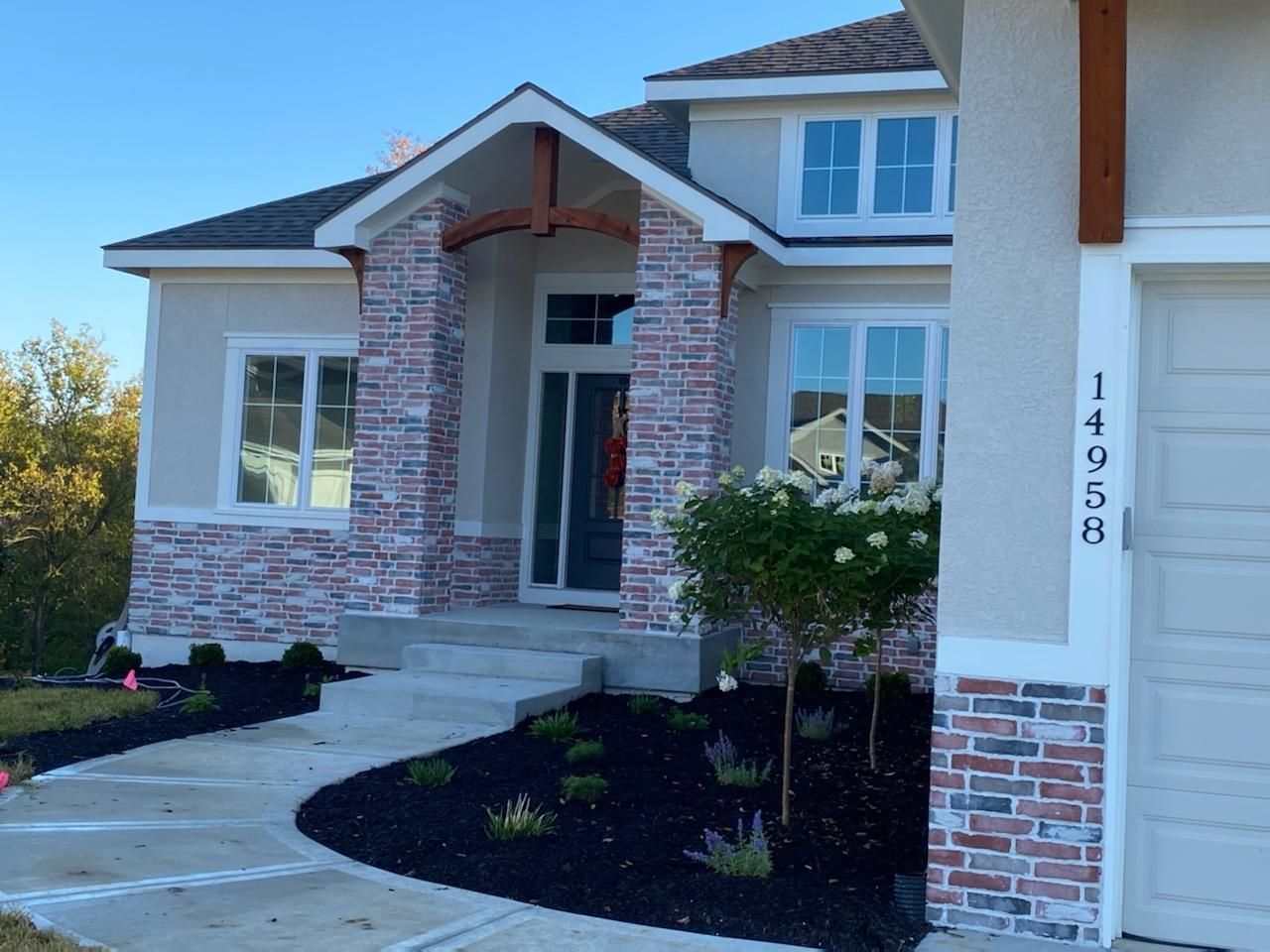 Modern suburban house with brick accents, white trim, a curved driveway, and a garage door number 14958