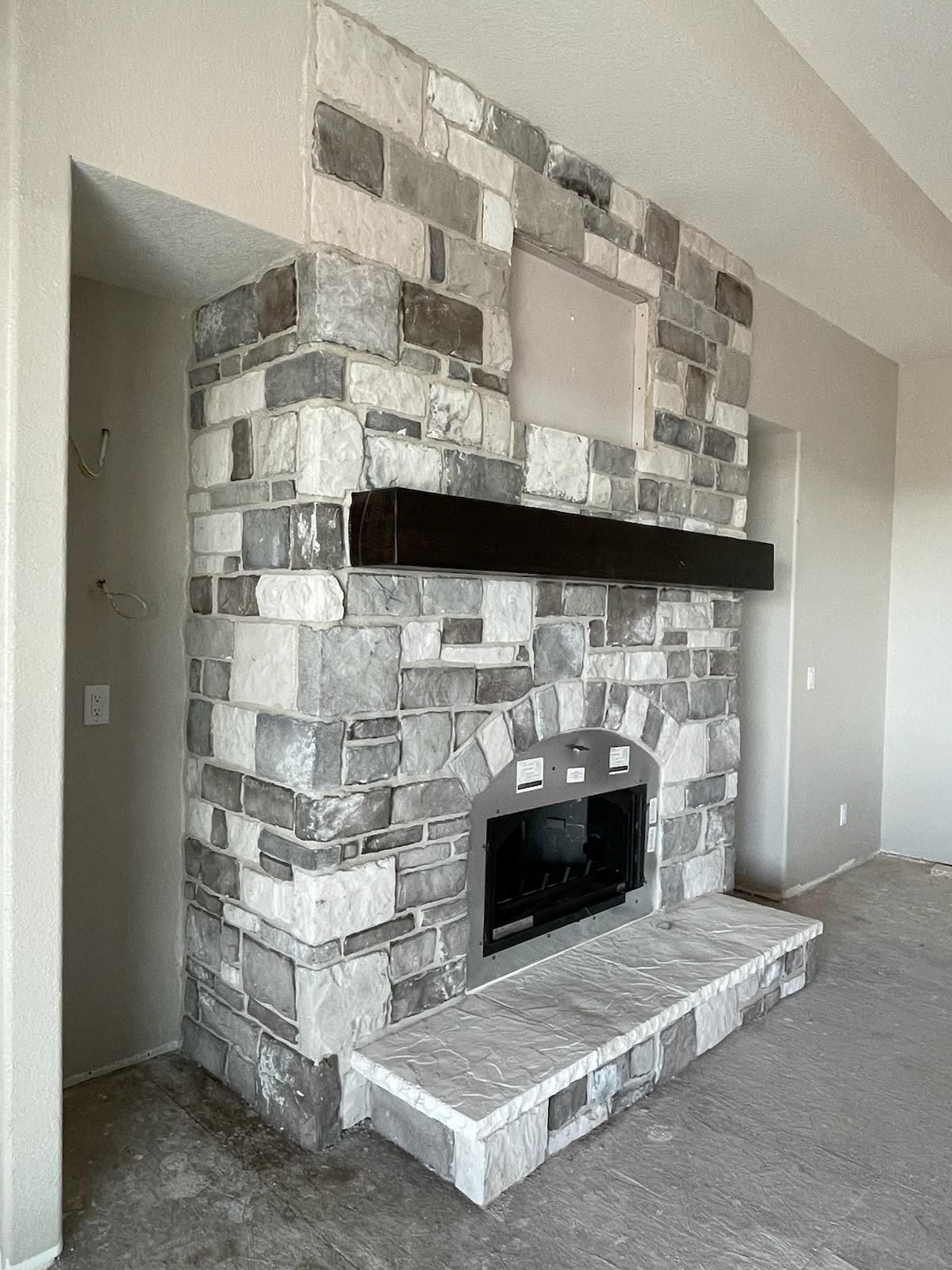 Stone fireplace with a raised hearth in a beige living room.