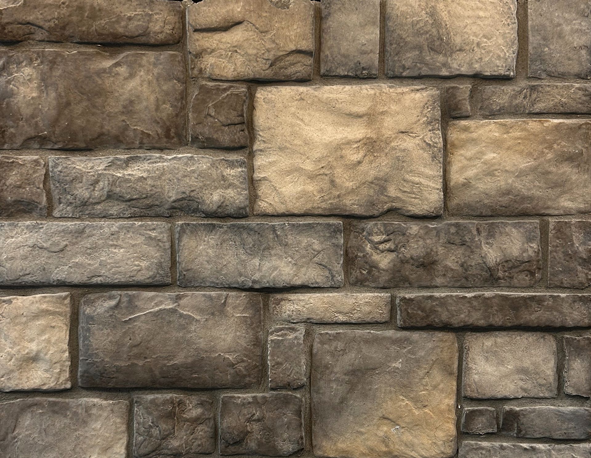 Close-up of a stacked stone wall with varied tan and gray rectangular blocks