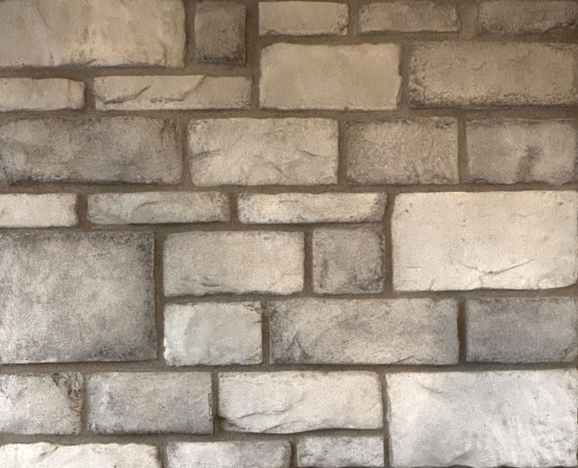 Close-up of a tan and gray stone wall with rectangular blocks and mortar lines
