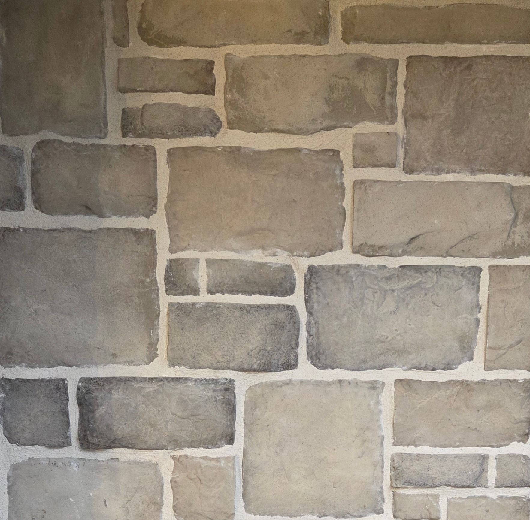 Stone wall with irregular gray and tan rectangular blocks.