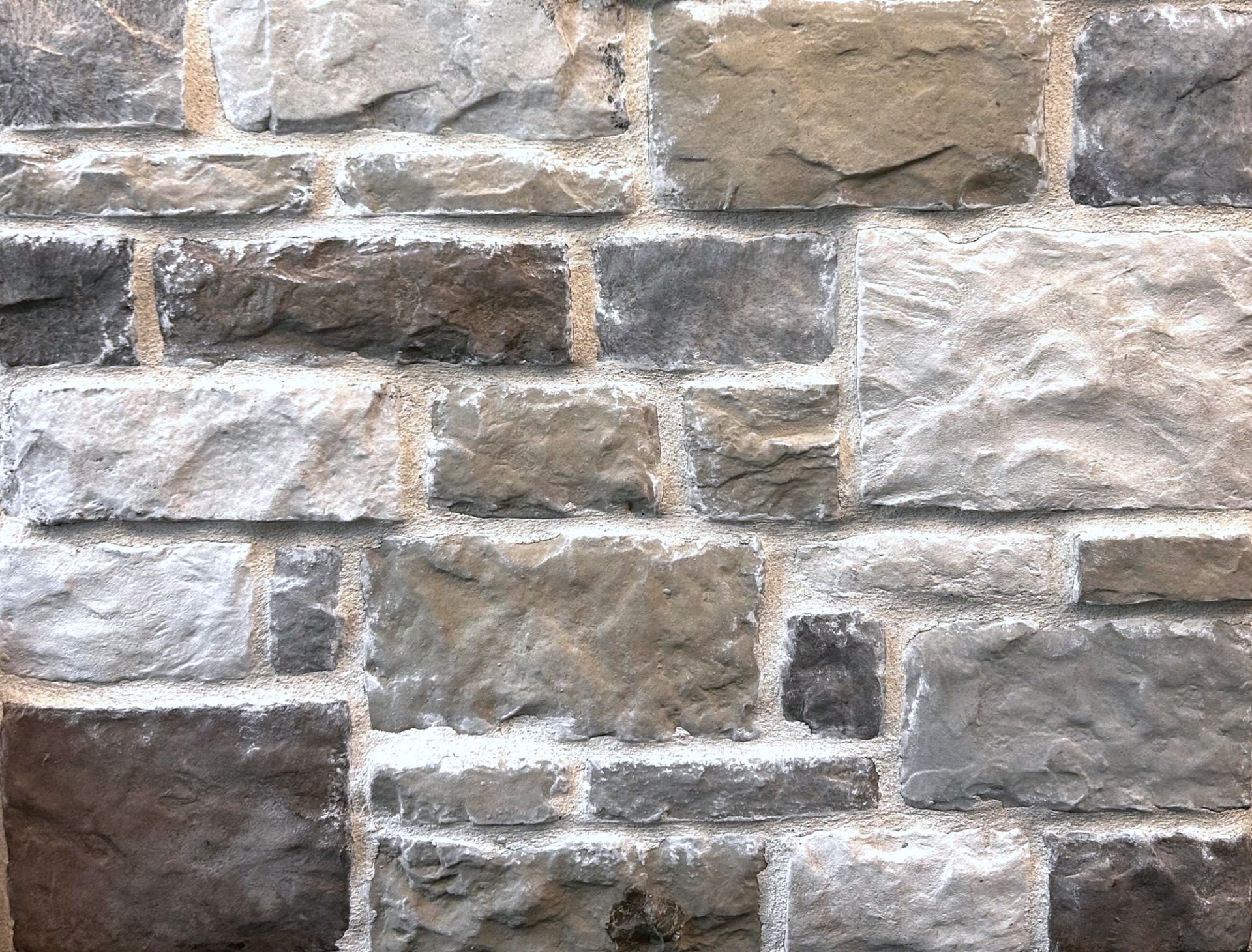 Close-up of a rustic stone wall with gray, tan, and brown blocks