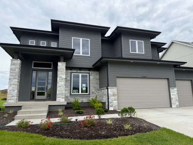 Modern two-story gray house with a double garage, front steps, and landscaped yard