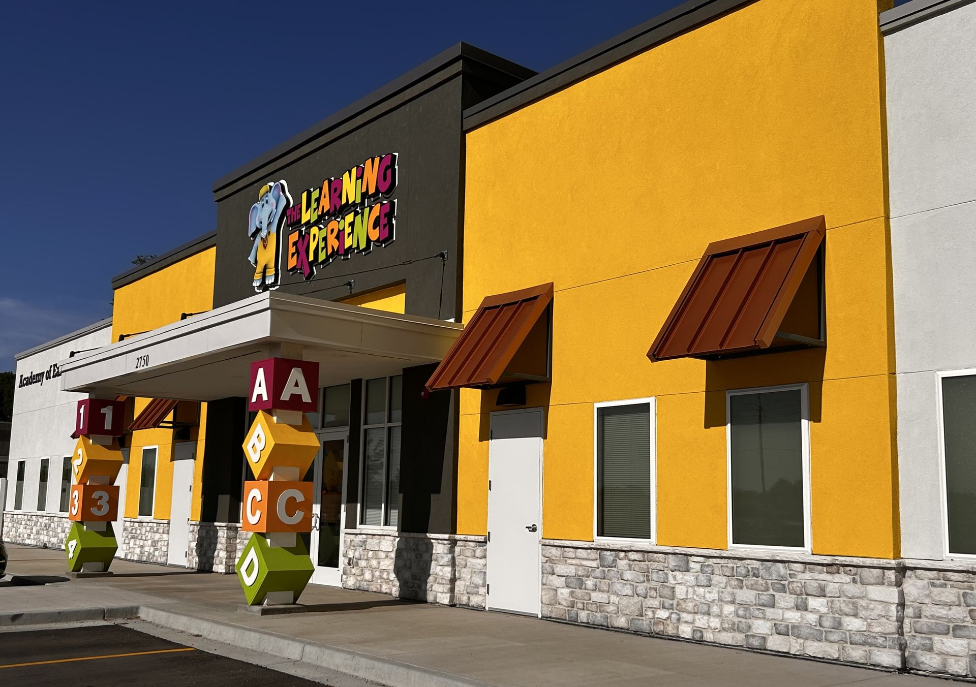 Yellow and white fast-food restaurant exterior with brown awnings and signage under a clear blue sky