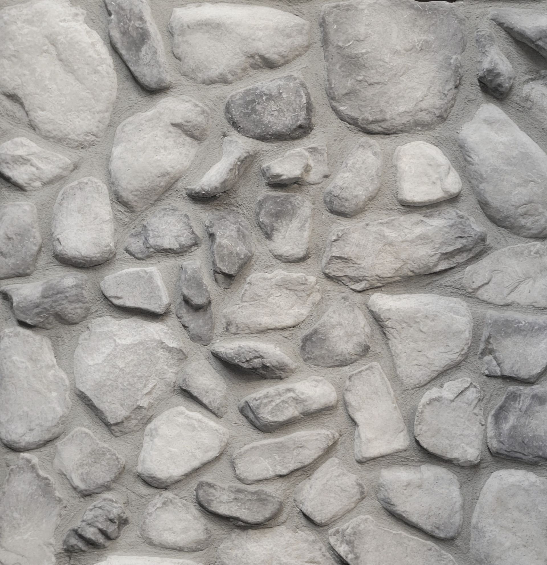 Gray stone wall with irregular rounded rocks and mortar texture