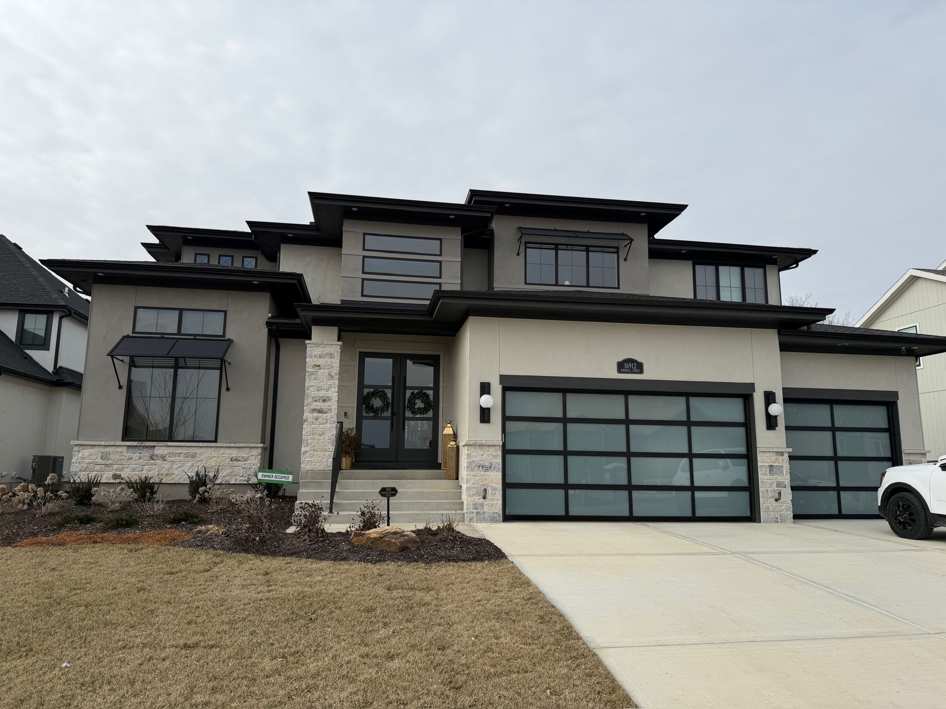 Modern two-story suburban house with gray garage doors and a driveway, viewed from the front