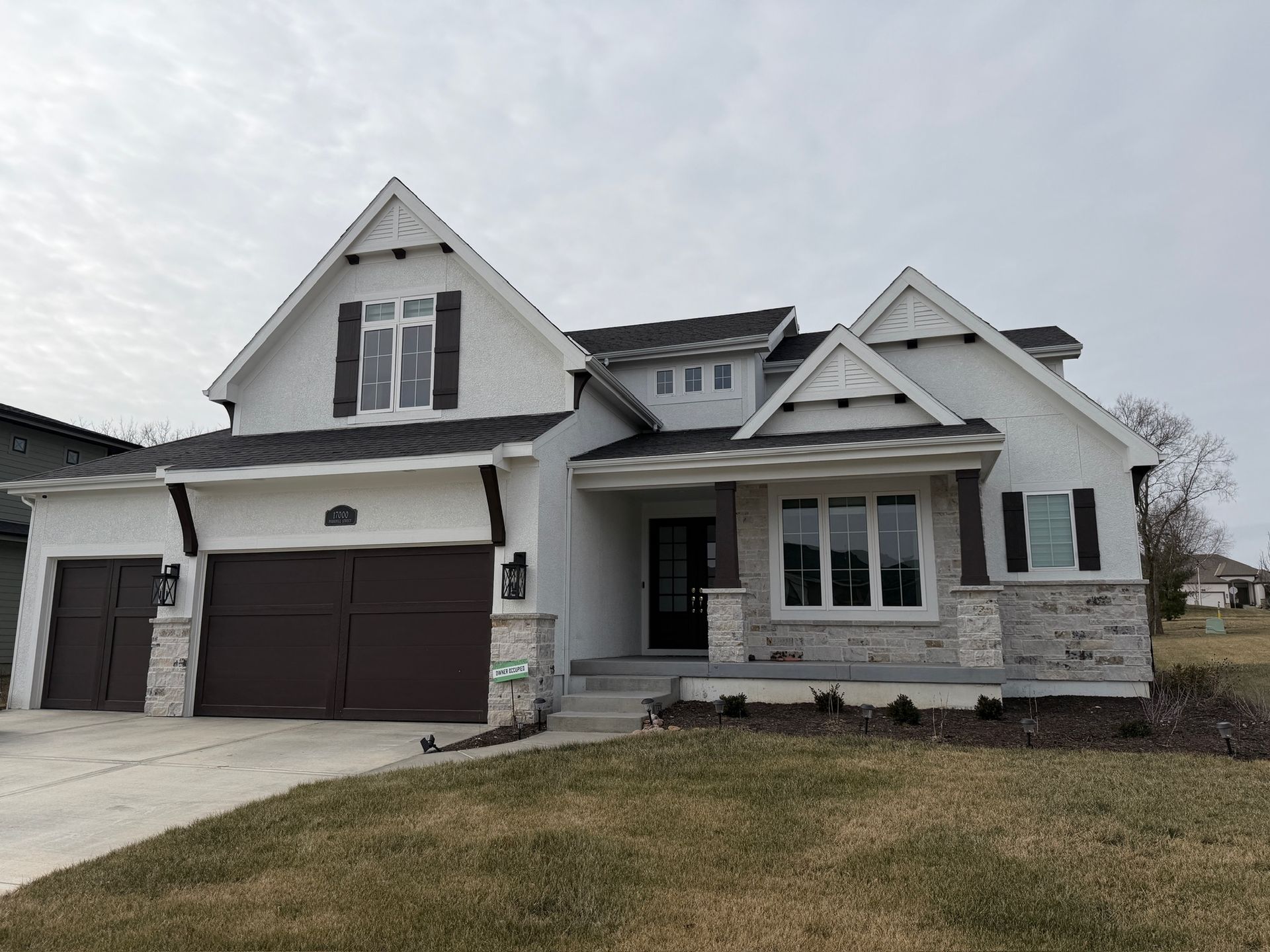 Modern gray-and-white suburban house with a two-car garage and front porch