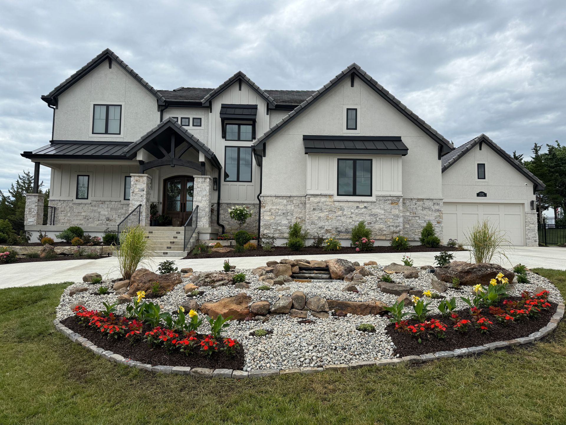 Large modern house with stone accents and a circular landscaped flower bed in front