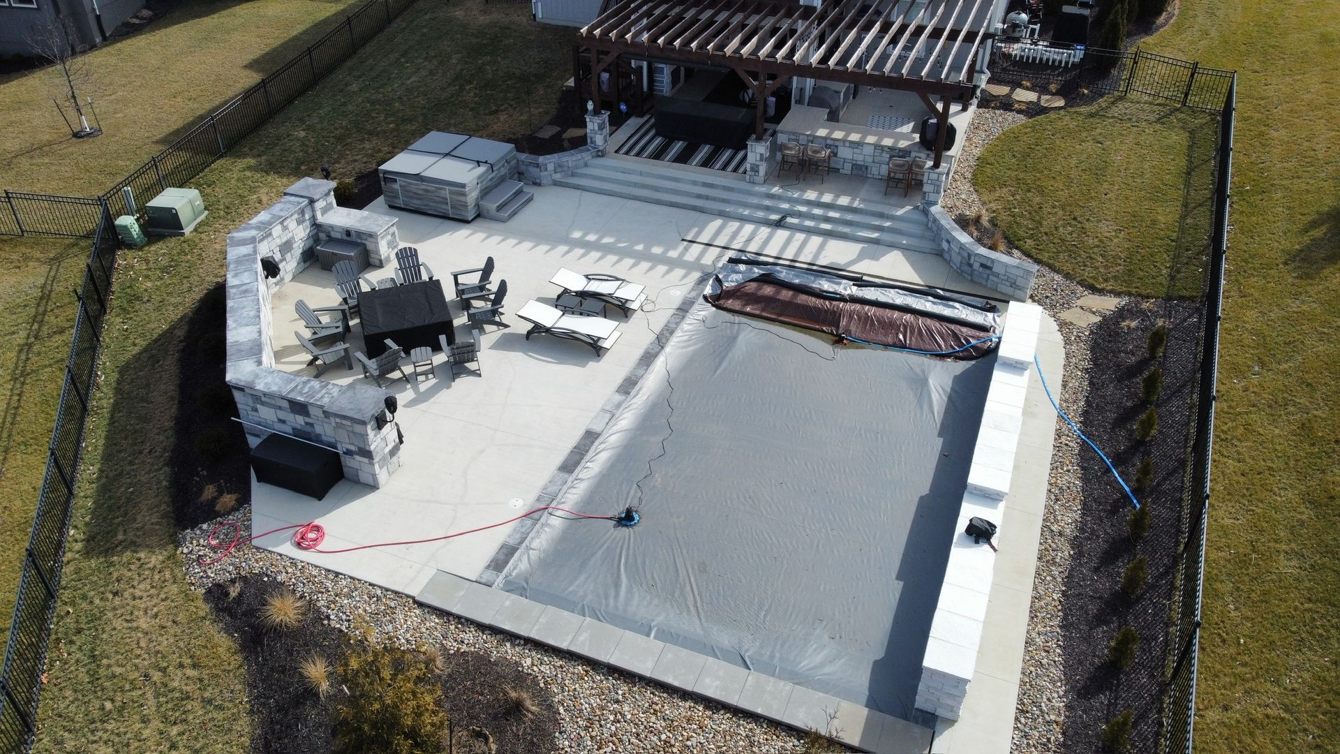 Aerial view of a white rooftop with HVAC units and a fenced perimeter beside a building.