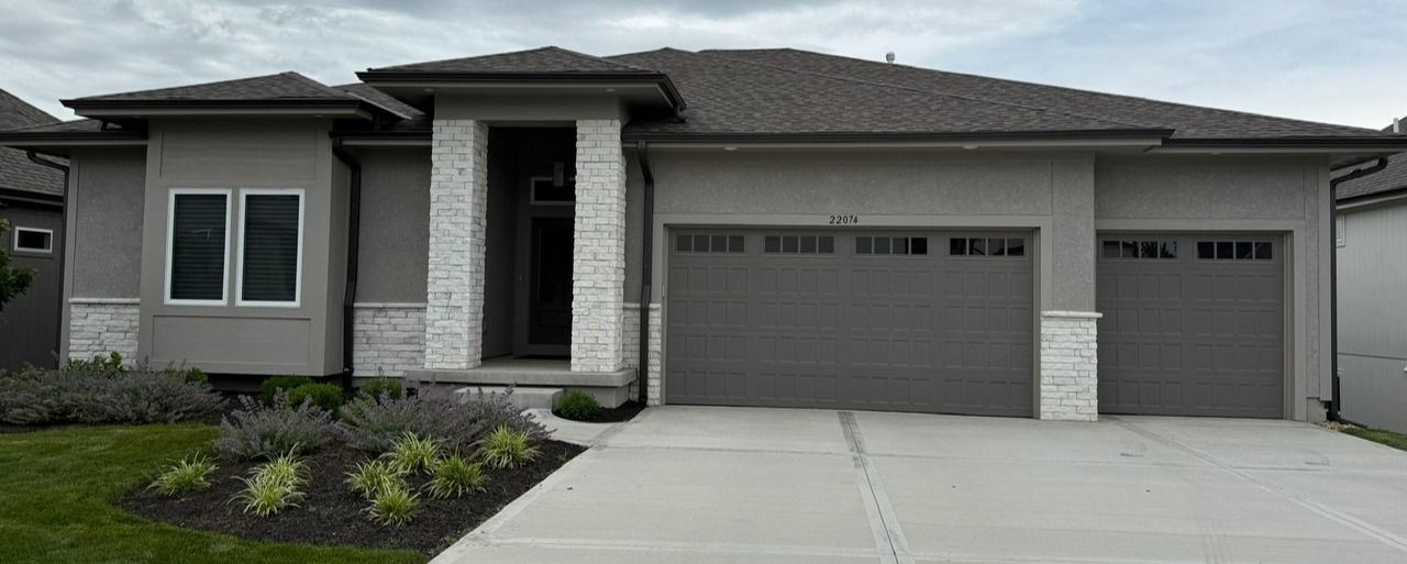 Modern single-story house exterior with gray siding, two-car garage, and landscaped front yard
