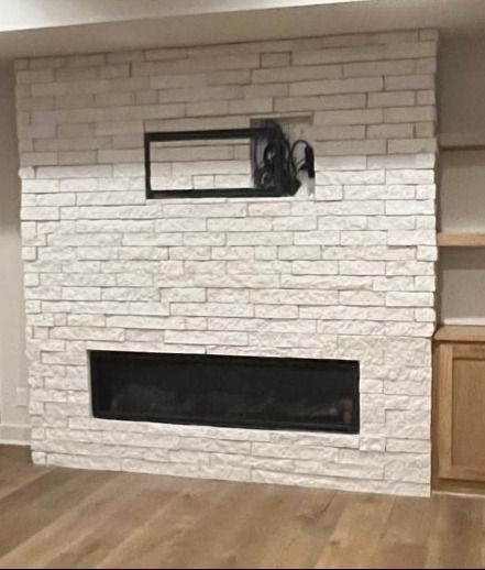 White brick fireplace wall with a long black firebox and a small rectangular window above it.