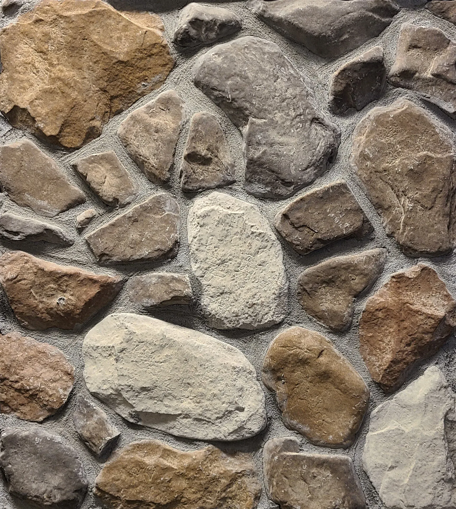 Close-up of a textured stone wall with irregular gray, tan, and brown rocks and white mortar