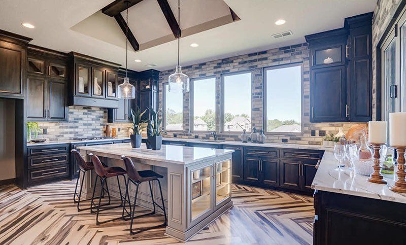 Bright modern kitchen with dark cabinets, white island, exposed beams, and large windows