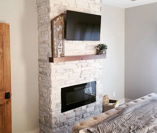 Modern living room with white brick fireplace, mounted TV, and black electric insert beneath a wooden mantel
