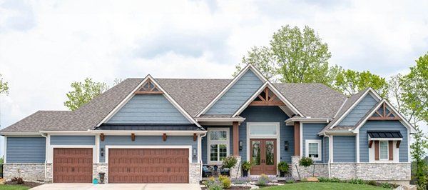 Suburban house with blue-gray siding, three-car garage, and landscaped front yard