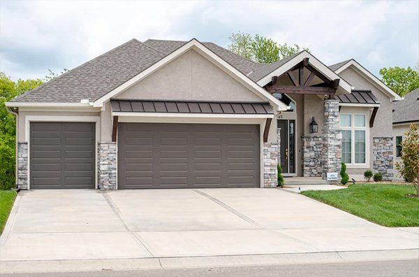 Suburban house with stone facade, double garage, and wide concrete driveway