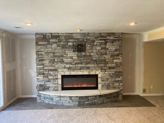 Living room with stone fireplace and curved hearth on beige walls and carpet