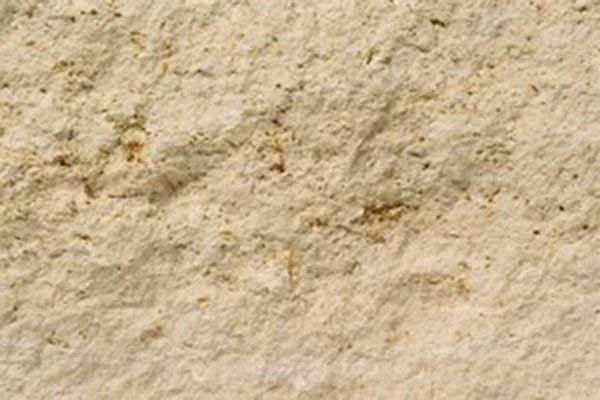 Close-up of a rough beige stone or textured wall surface