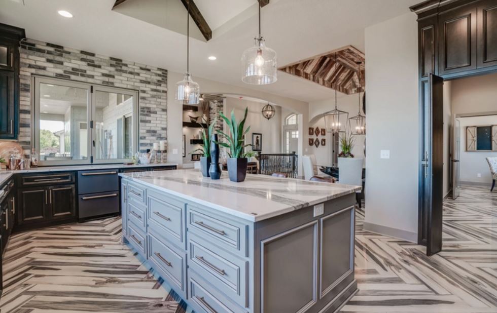 Modern kitchen with large island, dark cabinets, white marble countertops, and exposed wood ceiling beams