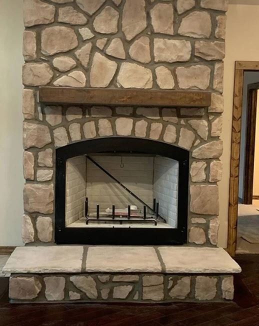 Stone fireplace with a black arched firebox and built-in stone hearth in a room
