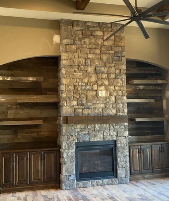 Stone fireplace with built-in wooden shelves and cabinets in a living room