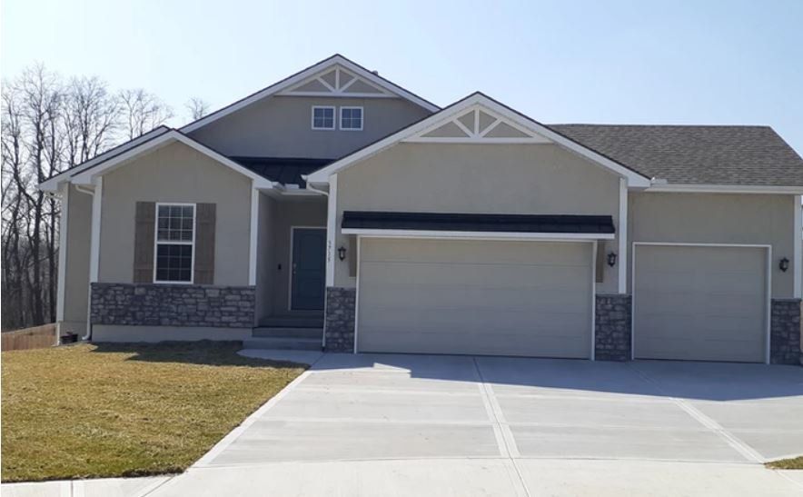 Suburban house with a two-car garage, stone accents, and a concrete driveway.