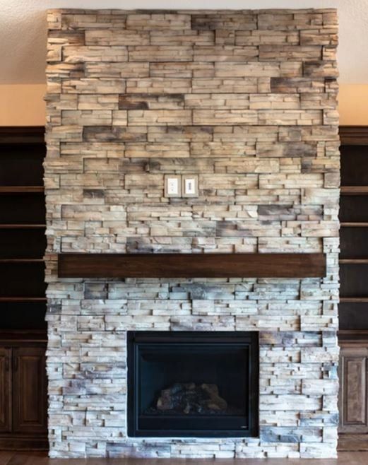 Stone fireplace wall with dark wood mantel and black fireplace insert in a living room